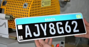 Uma pessoa segurando uma placa preta de automóvel.